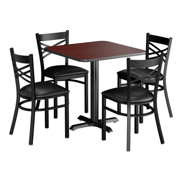 A square dining set with a reversible cherry and black table and four black cross back chairs with padded seats.