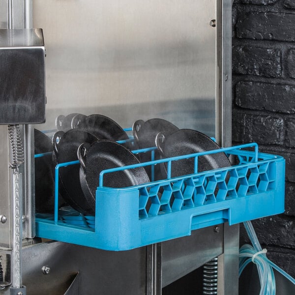A blue rack with black Lodge mini cast iron casserole dishes on it.