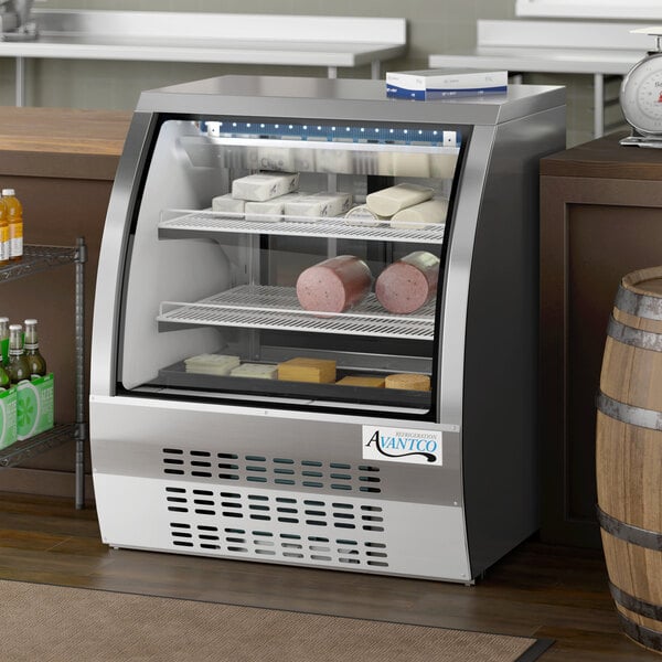 An Avantco stainless steel refrigerated deli case with curved glass filled with meats.