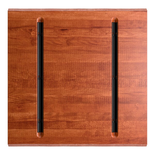 A square wooden surface with a reddish-brown finish and two parallel black metal rails attached lengthwise.