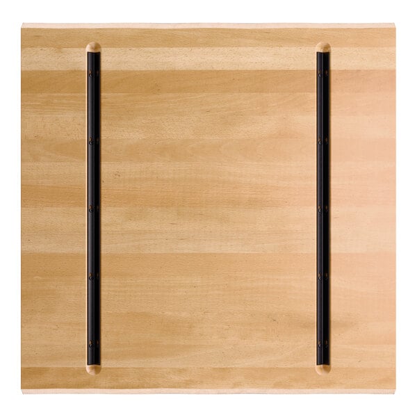 A square wooden tabletop with a honey maple finish and two parallel black metal strips running vertically.