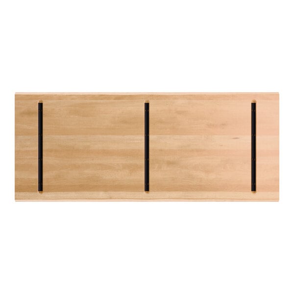 A rectangular wooden tabletop with a honey maple finish, featuring three parallel black metal strips running lengthwise.