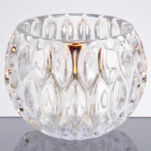 A Sterno Iris votive glass candle holder on a table.