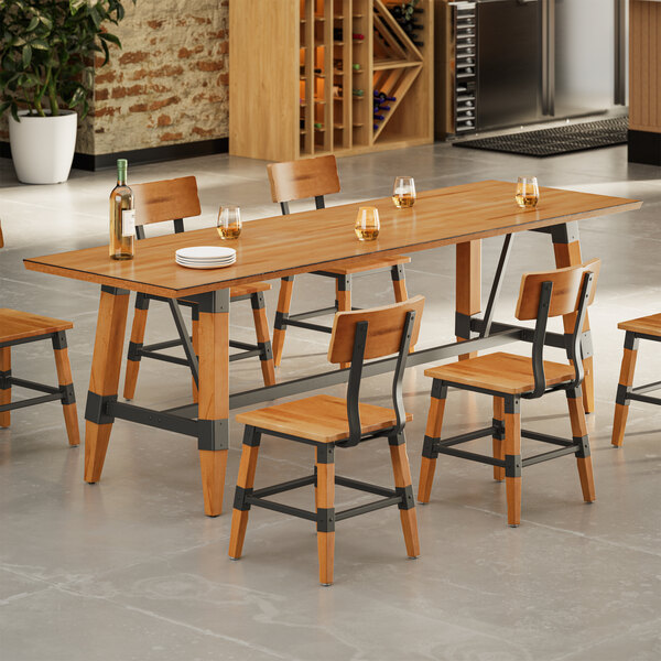 A rectangular wooden dining table with a honey maple finish, surrounded by matching chairs with metal accents, set in a modern kitchen or dining area.