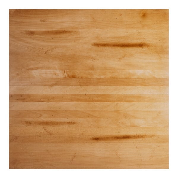 A close up of a Lancaster Table & Seating solid wood table top with a honey maple finish.