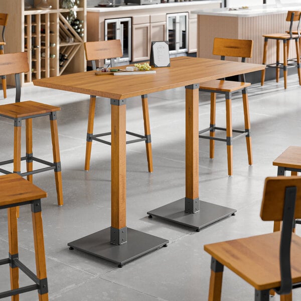 A Lancaster Table & Seating Industrial solid wood live edge bar height table with a honey maple finish and wooden stools with legs.