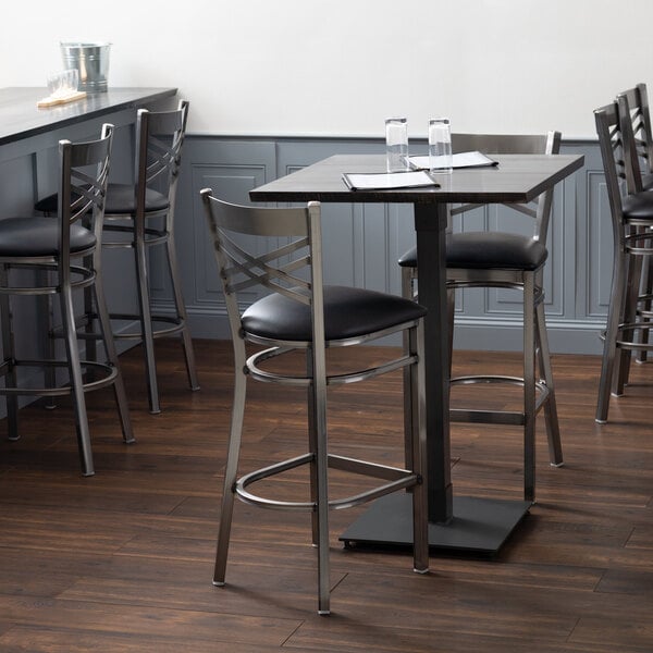 A Lancaster Table & Seating live edge bar height table with an antique slate gray finish on a table in a restaurant dining area.