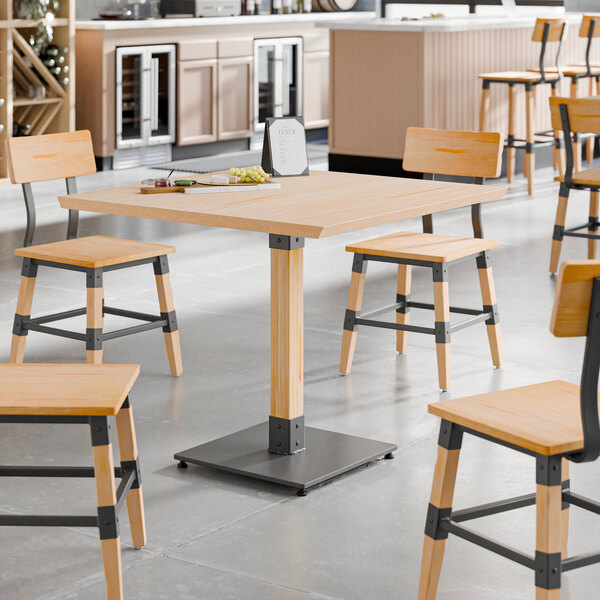 A Lancaster Table & Seating wooden table with live edge and bleached oak finish and black metal legs with chairs and a tray of food.
