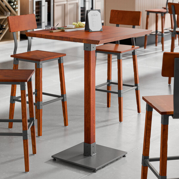 A Lancaster Table & Seating live edge bar height table with a rustic mahogany surface.