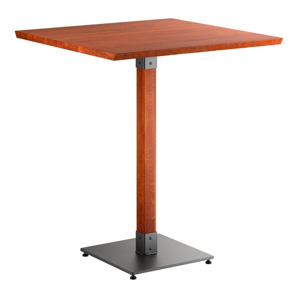 A square bar-height table with a solid wood top in a reddish-brown finish, supported by a single wooden pedestal and a square metal base.