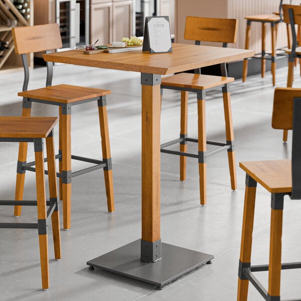 A bar height table with a honey maple finish and industrial metal accents.