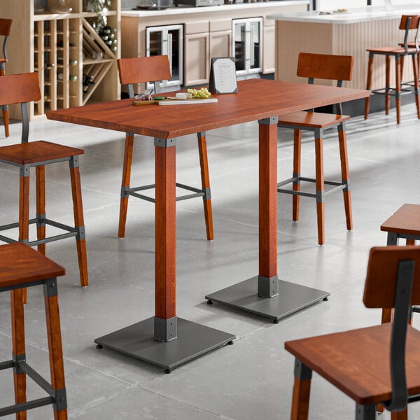 A Lancaster Table & Seating bar height table with a live edge and a rustic mahogany finish surrounded by chairs.