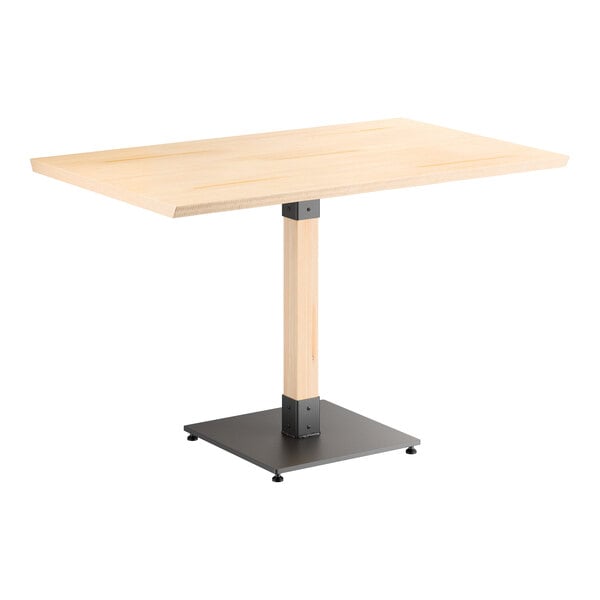 A rectangular table with a light wood top, a single central wooden support, and a black square metal base.
