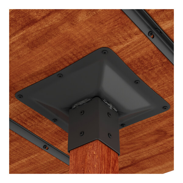 A close-up view of the underside of a solid wood live edge bar height table with a rustic mahogany finish and black metal hardware.