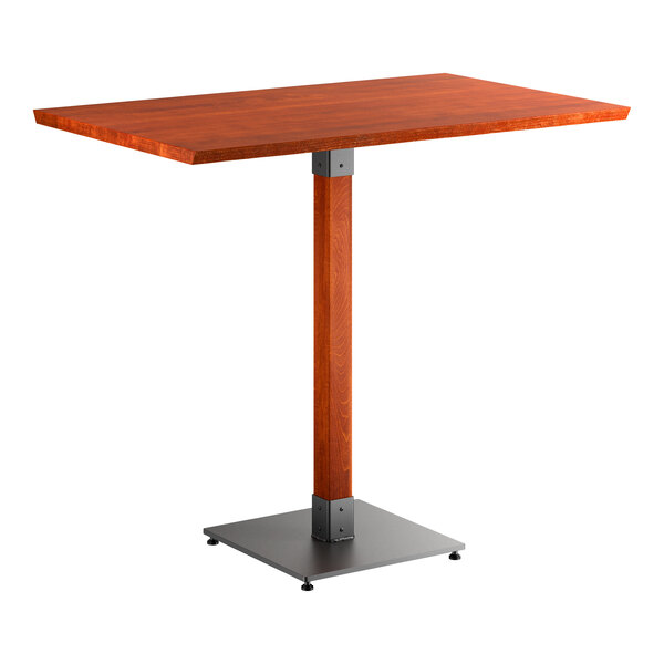 A rectangular bar-height table with a solid wood top in a reddish-brown finish, supported by a single wooden pedestal and a square metal base.