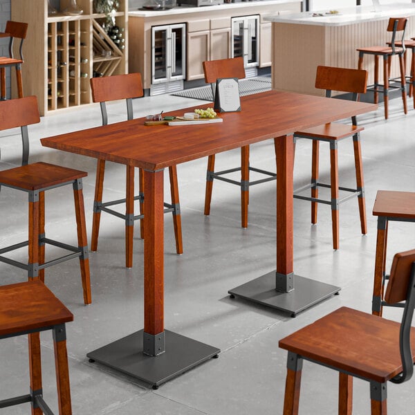 A Lancaster Table & Seating solid wood live edge bar height table with wooden chairs.
