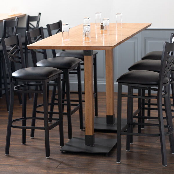 A Lancaster Table & Seating solid wood bar height table with a glass of water on it.