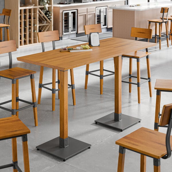 A Lancaster Table & Seating live edge wood bar height table with a honey maple finish.