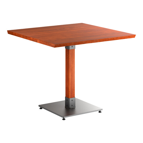 A square wooden table with a reddish-brown finish, supported by a single central wooden leg and a square metal base.