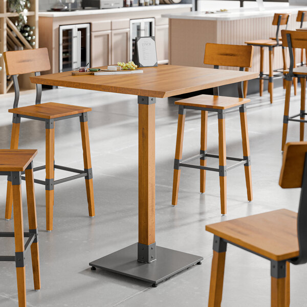 A Lancaster Table & Seating industrial wooden bar height table with stools.