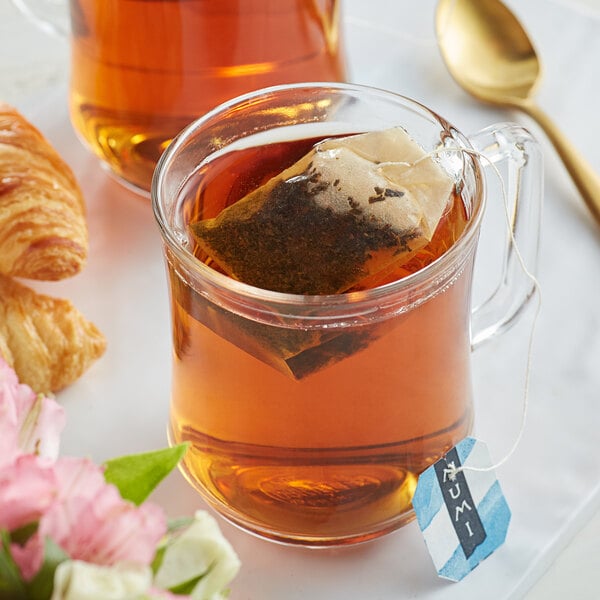 A glass mug with a Numi Organic Aged Earl Grey Tea bag in it.