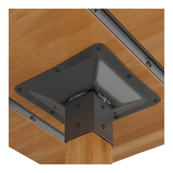 A close-up view of the underside of a wooden table with a metal mounting bracket securing the leg to the tabletop.
