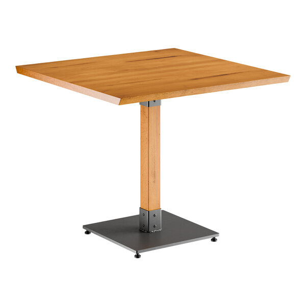 A Lancaster Table & Seating square wooden table with a live edge and metal base.