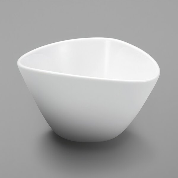A Oneida Mood bright white porcelain rice bowl with a small hole in the middle on a gray surface.