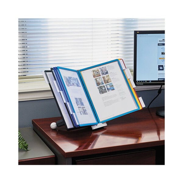 A Durable desktop reference system with assorted borders on a desk with a computer and a book holder.