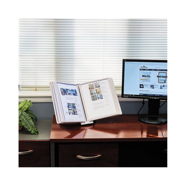 A Durable desktop reference system on a desk with a computer and a book open in it.
