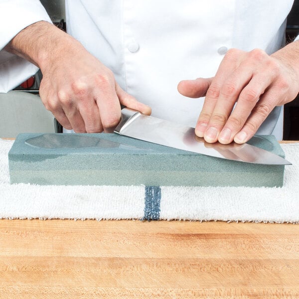 Chef sharpening a knife on a sharpening stone, or whetstone.