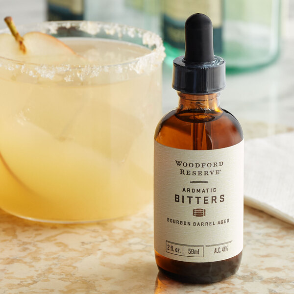 A Woodford Reserve bottle of bitters next to a glass of liquid.