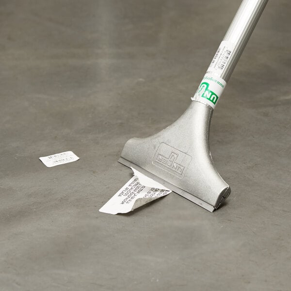 floor scraper removing a sticker off the tiled floor