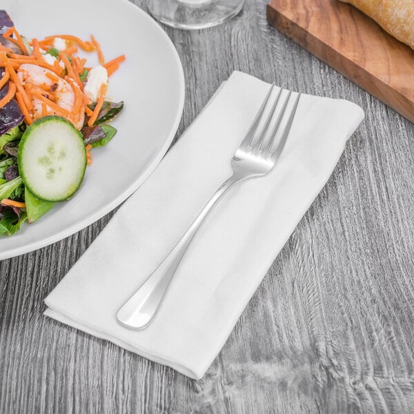 A plate of salad and a Oneida Baguette dessert fork on a napkin.