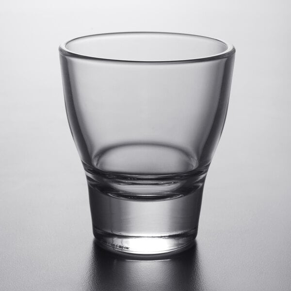 An Arcoroc clear glass shot glass on a table.