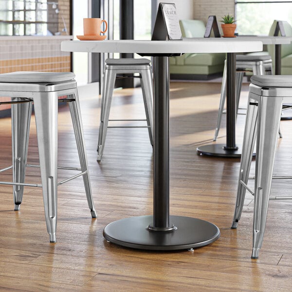 A Lancaster Table & Seating black cast iron counter height table base with a round table top.