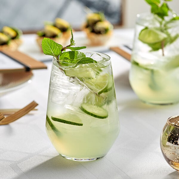 A close up of a glass of cucumber and lime drink with mint leaves.