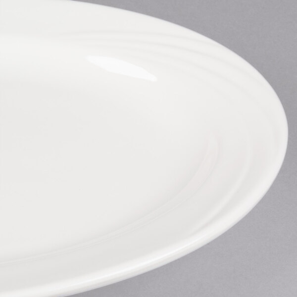 A close-up of a CAC Garden State bone white oval platter with a wavy rim.
