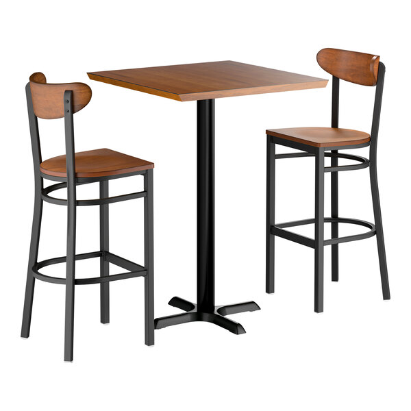 A bar-height table set with a square wooden tabletop and two matching bar stools, all featuring black metal frames and wooden seats and backs.