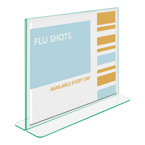 A clear, double-sided acrylic sign holder with green-tinted edges displaying a sign about flu shots.
