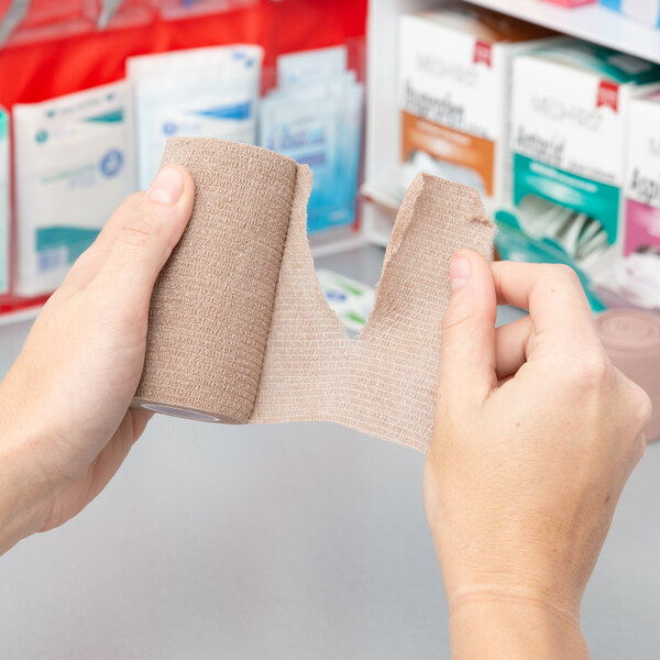 A person holding a roll of Medi-First self-adhesive wrap.