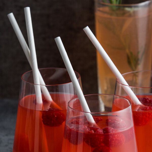 Три стакана с красным напитком, малиной и большими белыми соломинками