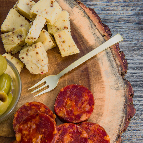 A Fineline gold plastic fork next to cheese and salami on a plate.