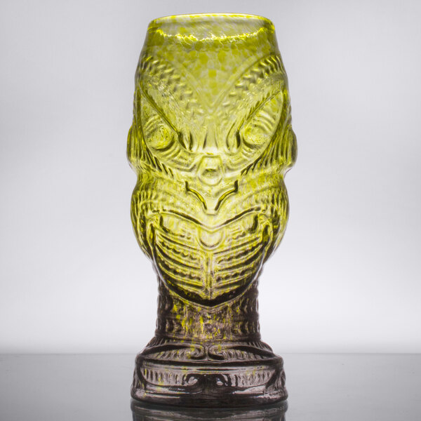 A close up of a green Head Hunter Tiki glass with a yellow design on it.