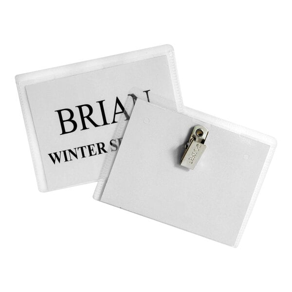 Two rectangular name badge holders are shown, one displaying a paper insert with text and the other showing a metal clip on the back.