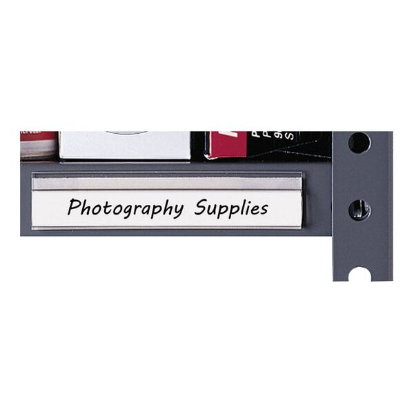A close-up of a shelf edge with a clear labeling strip displaying the text 'Photography Supplies.'