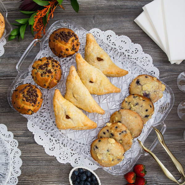 A Fineline Crystal Plastic catering tray of pastries and muffins on a table.