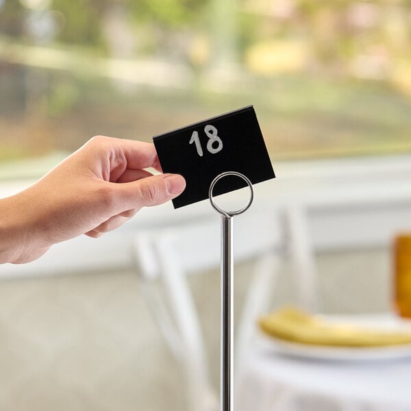A chrome menu or card holder with a black card displaying the number 18.