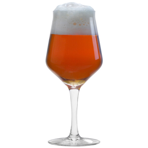 A close-up of a Stolzle stemmed beer glass full of amber beer with foam on top.