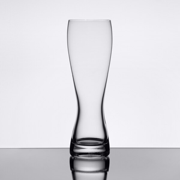 A Stolzle wheat beer glass on a table with a reflection.
